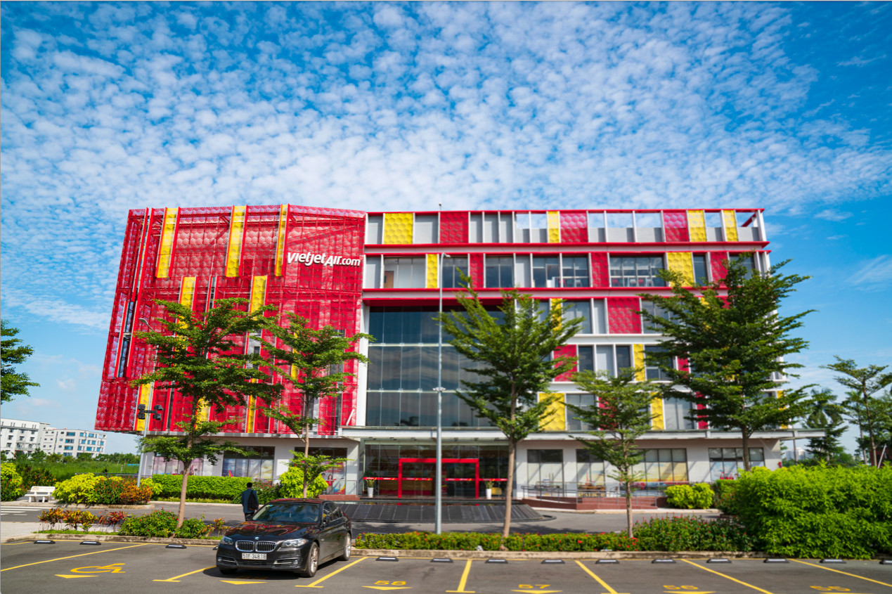 A red and yellow building with trees and a parking lotDescription automatically generated