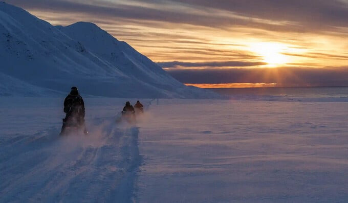 Các nhà khoa học di chuyển bằng xe trượt tuyết về khu định cư khi mặt trời lặn. Ảnh: Reuters