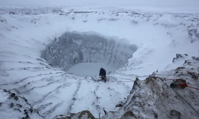 Một thành viên đoàn thám hiểm đứng ở rìa miệng hố phát nổ mới hình thành trên bán đảo Yamal. Ảnh: Reuters