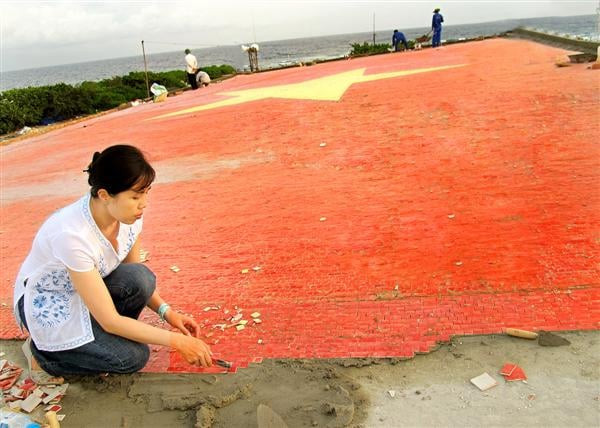 Họa sĩ Nguyễn Thu Thủy - tác giả công trình đang gắn những viên gốm nhỏ để hoàn thiện lá cờ