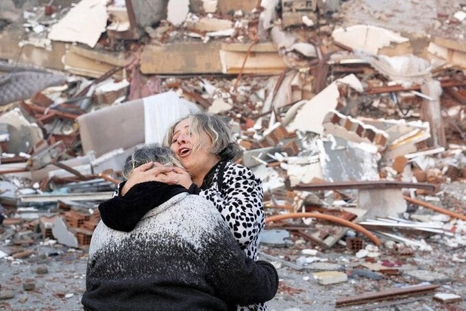 Những người còn sống sót ôm nhau bên cạnh những đống đổ nát sau động đất ở vùng Hatay, Thổ Nhĩ Kỳ ngày 7-2 - Ảnh: Reuters