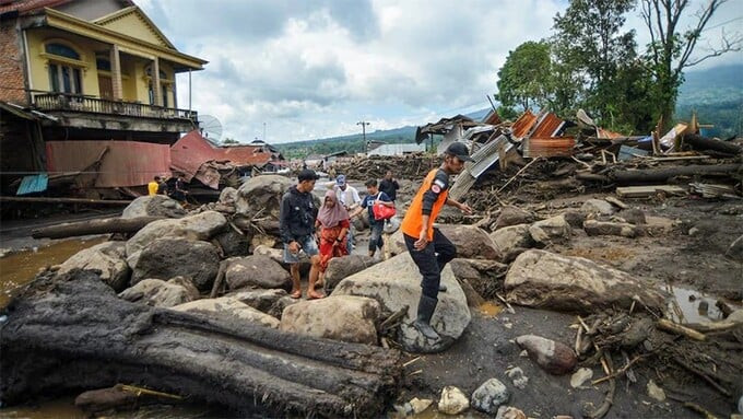 Người dân địa phương đi qua khu vực chịu ảnh hưởng của mưa lớn. Ảnh: Reuters