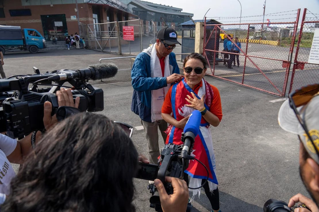 Kim Lal Gautam đặt lá cờ Nepal lên người Phunjo Lama khi cô trở về sân bay ở Kathmandu. Ảnh: Niranjan Shrestha/AP