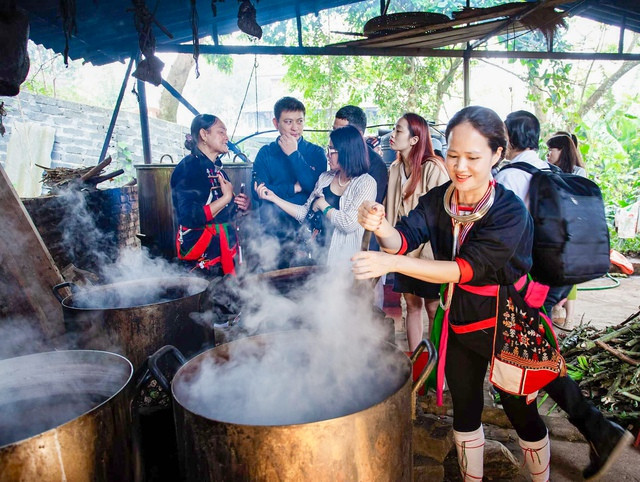 Du khách tìm hiểu quy trình nấu cao thuốc của người Dao tại huyện Ba Vì (Hà Nội). Ảnh: Tổ quốc.