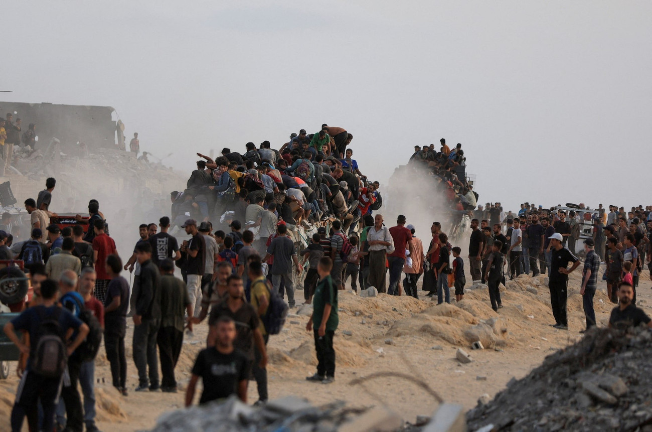 Người dân Palestine trèo lên xe tải chở hàng viện trợ. (Ảnh: Reuters) olse3jijxzknvhstyk5fjtzk4e.jpg