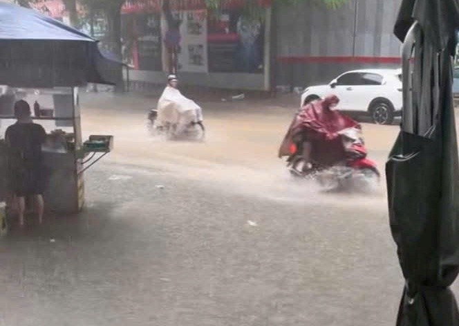 Nước ngập gần nửa bánh xe máy trên đường Nguyễn Tuân trong lúc mưa vẫn tiếp diễn. 2.jpg