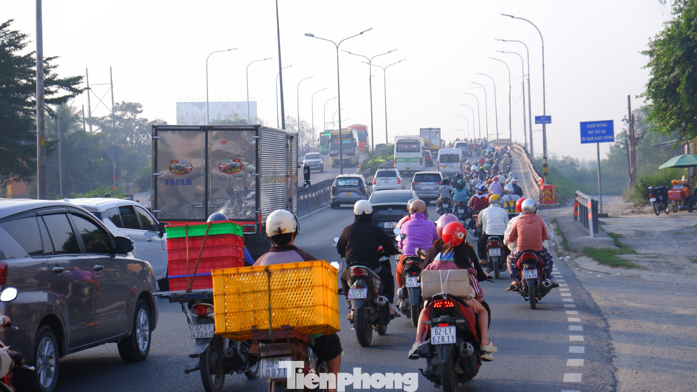 Dọc tuyến đường, dễ dàng bắt gặp hình ảnh người dân chạy xe máy về quê, phía sau chất đầy quà bánh, lịch Tết, túi xách, balô…. Người dân bắt đầu kỳ nghỉ kéo dài 4 ngày với tâm trạng háo hức. Trong ảnh: Phương tiện tấp nập qua cầu Bình Điền 1 trên đường Lê Khả Phiêu (hướng về các tỉnh, thành miền Tây). tp-ve-que-1010.jpg