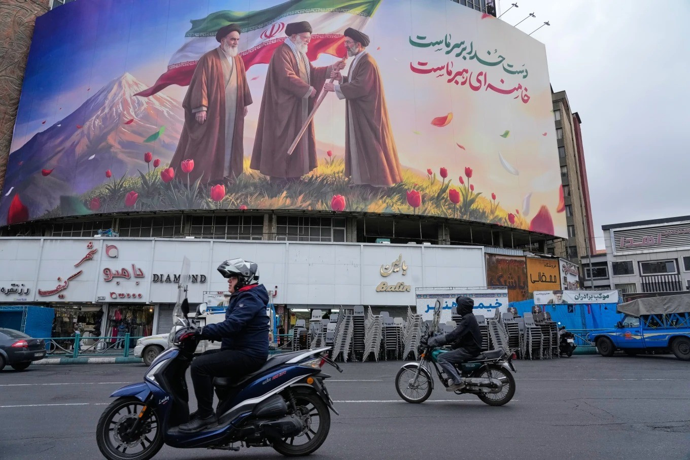 Một tấm biển có hình ảnh cố Lãnh tụ Tối cao Iran - Ayatollah Ali Khamenei (giữa) trao quốc kỳ cho con trai và người kế nhiệm của ông - Ayatollah Mojtaba Khamenei (phải), trong khi người sáng lập nhà nước Cộng hòa Hồi giáo Iran - Ayatollah Ruhollah Khomeini đứng bên trái, tại một quảng trường ở trung tâm Tehran. (Ảnh: AP) image-48.jpg