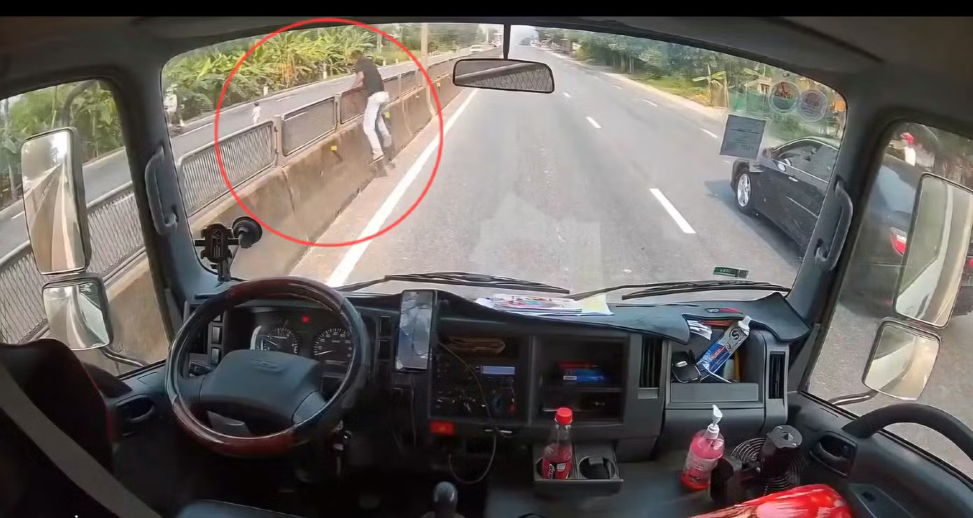 Tài xế Tố dừng xe khẩn cấp giữa quốc lộ, sau đó trèo qua dải phân cách để ứng cứu kịp thời bé gái thoát tình huống nguy hiểm. Ảnh cắt từ clip Tài xế ‘liều’ dừng xe giữa quốc lộ cứu bé gái thoát tình huống nguy hiểm - Ảnh 1.
