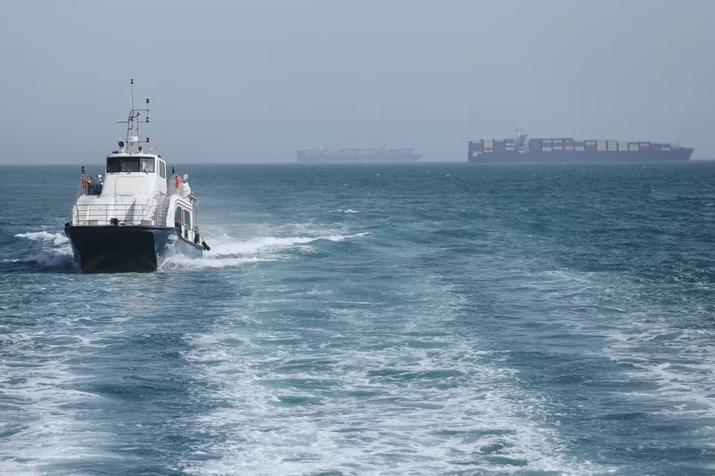 Một tàu tuần tra đi qua vùng biển nơi các tàu hàng neo đậu tại eo biển Hormuz, ngày 2/5. (Ảnh: AP) Iran ra tay bất ngờ, Tổng thống Mỹ Trump phân vân nên đánh tiếp hay dừng - Ảnh 1.
