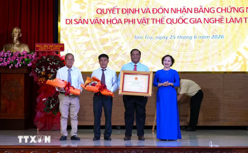 Bà Trần Thị Đoan Quang, Giám đốc Bảo tàng tỉnh Tây Ninh trao Bằng chứng nhận Di sản Văn hóa Phi vật thể Quốc gia đối với Nghề làm trống Bình An cho lãnh đạo Ủy ban Nhân dân xã Tân Trụ. (Ảnh: Thanh Bình/TTXVN)