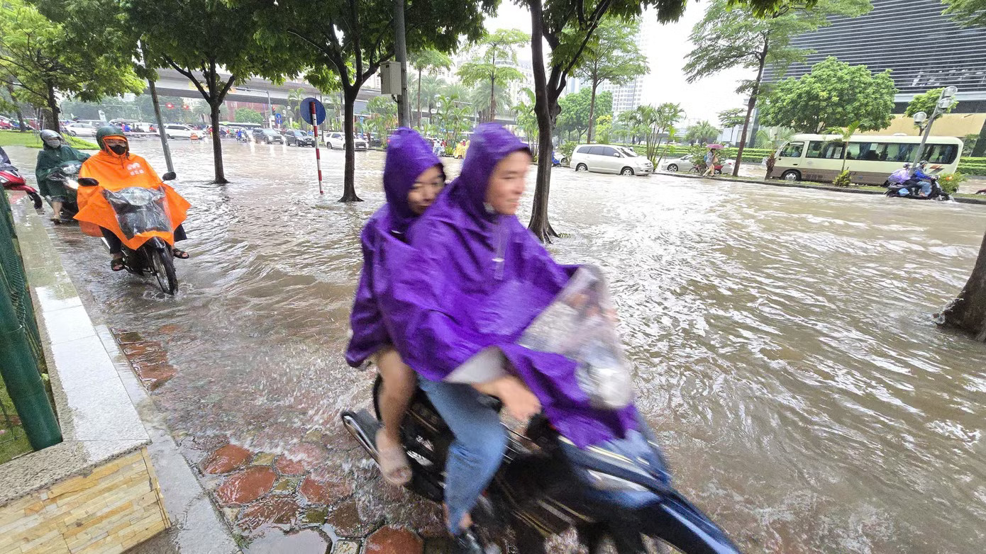 Nước ngập sâu tại ngã tư Keangnam (nút giao Dương Đình Nghệ - Phạm Hùng), nhiều phương tiện cố leo lên vỉa hè để thoát thân nhưng vẫn bị mắc kẹt. Hà Nội: Mưa lớn kéo dài, nhiều tuyến phố ngập, giao thông ùn ứ - Ảnh 19.
