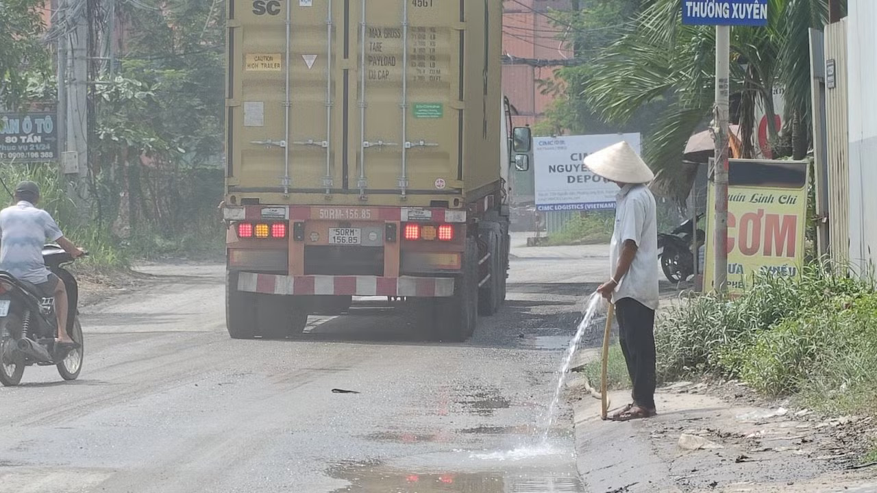 Người dân sinh sống, buôn bán trên tuyến đường Nguyễn Xiển buộc phải xịt nước để giảm bụi, chấp nhận sống chung mỗi ngày. Ảnh: Khoa Nam. Ám ảnh con đường tử thần ở TPHCM, mới vá xong lại nát bét - Ảnh 9.