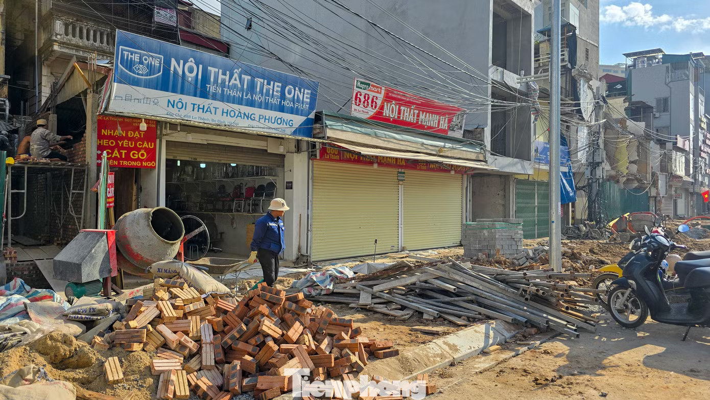 Tại một số vị trí, vỉa hè và phần đường trước cửa hàng chưa hoàn thiện, vật liệu xây dựng còn ngổn ngang, gây khó khăn cho việc đi lại và kinh doanh. Hàng quán mở cửa trở lại trên tuyến Hoàng Cầu - Voi Phục mới - Ảnh 3.