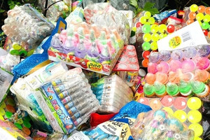 Hàng trăm gói kẹo đồ chơi trẻ em yêu thích đổ lộ thiên cạnh bãi rác